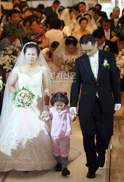  혼인식을 올리지 못하고 동거를 해온 12쌍 부부의 합동 혼인식이 2일 수원 리젠시호텔에서 열렸다. 아이의 손을 잡은 한 동거부부가 행복한 표정으로 식장에 들어서고 있다.