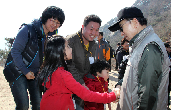 출입기자들과 청와대 뒤편 북악산 산행에 나선 이명박 대통령이 20일 오전 북악산에서 산행중인 한 가족을 만나 인사하고 있다./연합뉴스