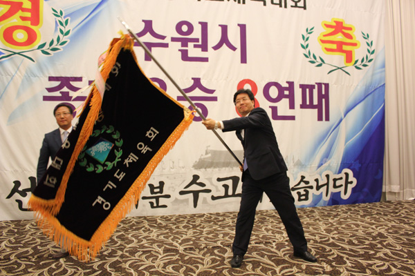 16일 수원 노블레스웨딩컨벤션에서 열린 제58회 경기도체육대회 성과보고회에서 종합우승 8연패를 달성한 수원시체육회장인 염태영 수원시장이 이내응 사무국장으로 부터 우승기를 봉납 받은 뒤 흔들고 있다./제공=수원시체육회