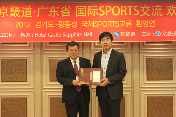 22일 수원 호텔캐슬에서 진행된 ‘2012 경기도·광동성 국제스포츠교류 환영연’에서 이진수 경기도문화체육관광국장(오른쪽)과 차이웨이슝 광동성 체육총회 부주석이 양국의 우호를 다지는 선물을 교환한 뒤 기념촬영을 하고 있다./제공=경기도생활체육회