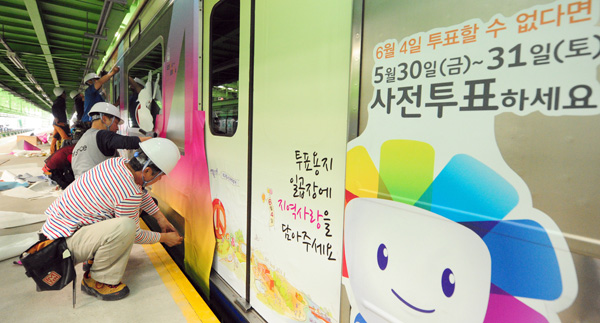 14일 화성 병점 전철차량기지에서 중앙선거관리위원회 관계자들이 전동차에 선관위 캐릭터(참참·바루·알리)와 사전투표·투표참여 문구 등을 랩핑하고 있다. 중앙선관위는 15일부터 선거일인 다음달 4일까지 1일 6회 ‘투표열차’를 운행할 예정이라고 밝혔다./노경신기자 mono316@