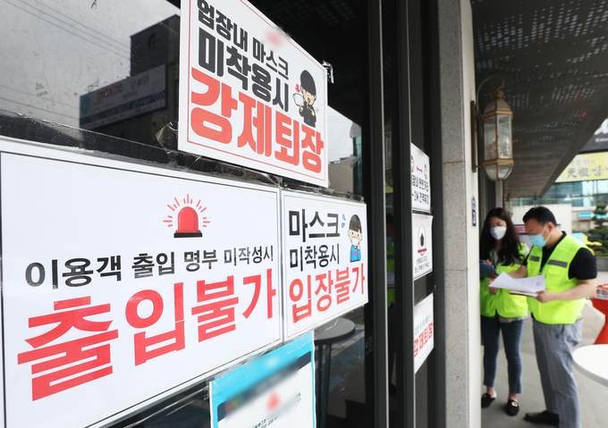 지난 5월 11일 경기도 수원시의 한 클럽에서 공무원들이 신종 코로나바이러스 감염증(코로나19) 확산 방지를 위한 집합금지 행정명령서를 붙이고 있다. (사진=연합뉴스)