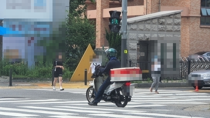 배달대행업체 라이더가 보행자 신호(초록불)에 횡단보도 위에서 신호대기하고 있다.(사진=김기현 수습기자)