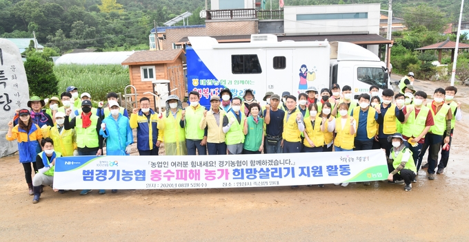 안성 죽산면 일대 수해복구 현장 지원에 나선 범경기농협 임직원들이 웃으며 기념촬영을 하고 있다. (사진=경기농협) 