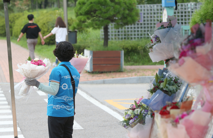지난 21일 국립 인천대학교 송도캠퍼스에서 한 화훼 상인이 양손에 꽃을 들고 있다. (사진=연합뉴스)
