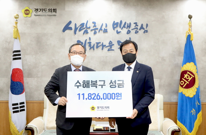 경기도의회 장현국 의장이 윤신일 대한적십자사 경기도지사 회장에게 성금을 전달하고 있다(사진=경기도의회 제공)