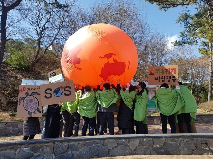 기후위기경기비상행동 활동가들이 뜨거워진 지구가 인간을 덮치는 퍼포먼스를 연출하고 있다. (사진=기후위기경기비상행동 제공)