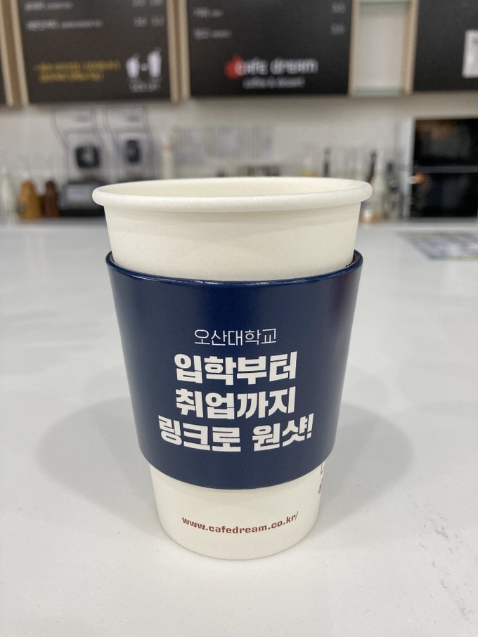 오산대학교 사회맞춤형학과중점형사업단니 LINC+ 사업 홍보를 위해 제작한 컵홀더 2000개를 종합정보관 북적북적(book적book적) 카페에 전달했다. /오산대학교 제공