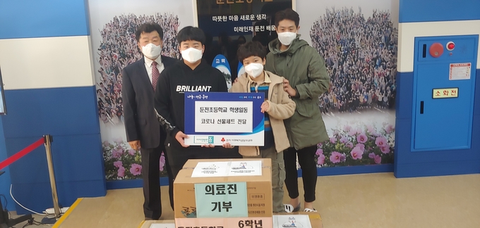 군포시보건소 직원들이 둔천초둥학교 양호식 교장과 둔전초등학교 6학년 학생들로부터 선물을 받았다. (사진=군포시 제공)