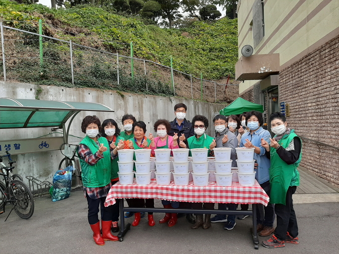 오산시 남촌동새마을부녀회 , 지역 봉사자, 행정복지센터 직원 등이 지난 21일 남촌동행정복지센터 앞마당에서 저소득층을 위한 김치 나눔 행사를 진행 후 기념촬영을 하고있다.( 사진=오산시 남촌동새마을부녀회 제공)