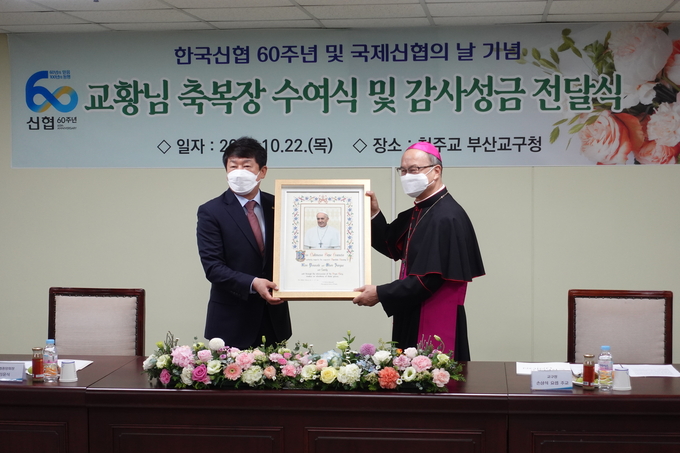 김윤식 신협중앙회장이 1,300만 신협 이용자와 임직원을 대표해 천주교 부산교구청 손삼석 요셉 주교로부터 프란치스코 교황 축복장을 받았다. (사진=신협중앙회 제공)
