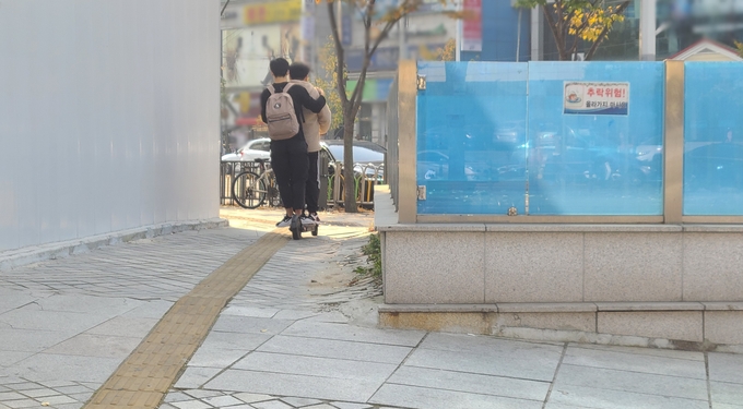 27일 수원시청역 인근에서 헬맷도 착용하지 않은 남성 2명이 전동 킥보드를 함께 타고 이동하고 있다. (사진=신연경 기자) 