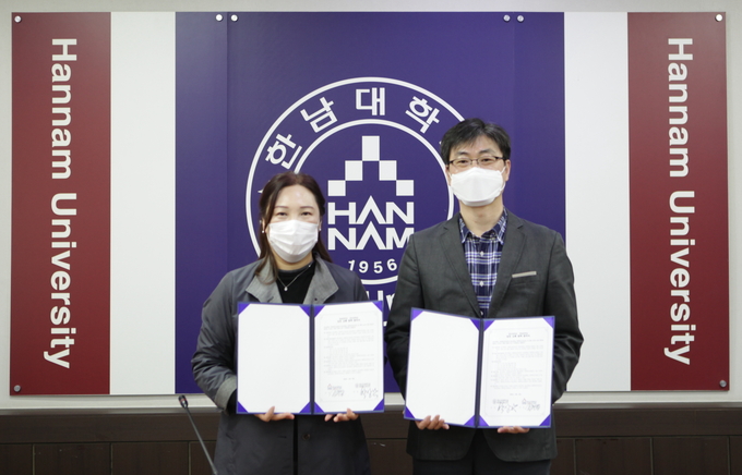한신대 조현식 팀장과 한남대 권선영 팀장이 협약서를 교환하고 기념사진을 찍고 있다. .(사진=한신대학교 제공)