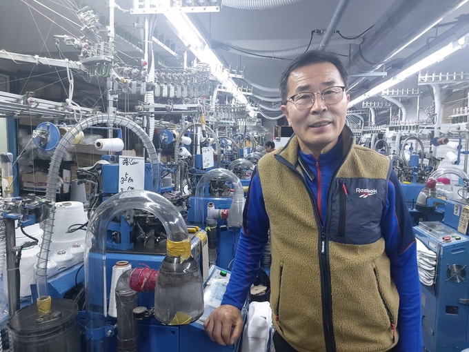 권순호 준희어패럴 대표가 공장 기기 옆에서 미소를 짓고 있다. (사진=편지수 기자)