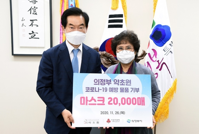 원영숙 약초원 대표가 안병용 의정부시장에게 마스크를 전달하고 있다.