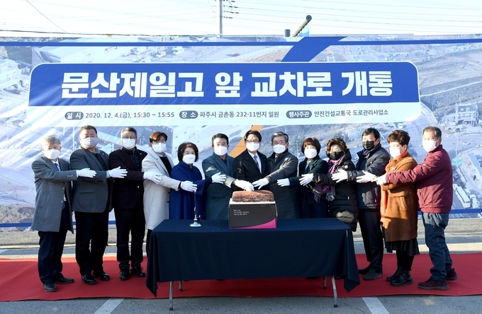 문산제일고 앞 방호벽 개통식 중 축하떡 앞에서 내빈들이 기념촬영을 하고 있다 (사진=파주시 제공)