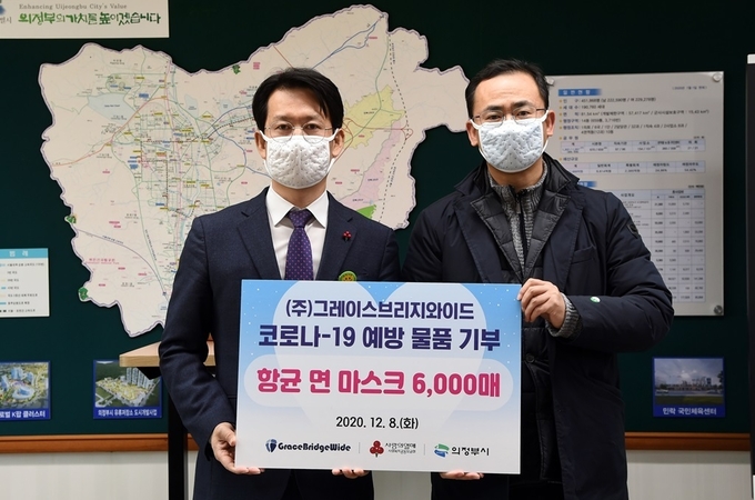 윤일호 대표(우측)가 황범순 의정부 부시장에게 마스크를 전달하고 있다.
