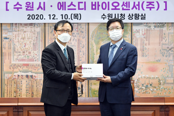 10일 수원시청 상황실에서 수원시와 SD바이오센서가 '코로나19 공동대응을 위한 업무협약'을 맺었다. 협약 체결에 이어 신속항원검사 키트 기증 후 염태영 시장(사진 오른쪽)과 이효근 SD바이오센서 대표가 함께 기념촬영을 하고 있다. (사진=수원시 제공)