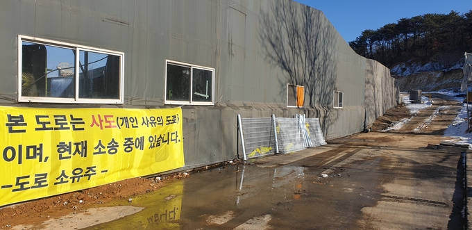 개발사업자와 소유자들 간 법적분쟁으로 논란이 되고 있는 사도에 통행제안을 알리는 현수막이 걸려있다. (사진=천용남기자)