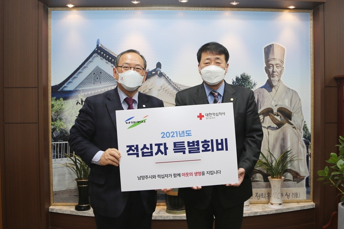 이철영 남양주시의회 의장(오른쪽)이 대한적십자사 경기도지사 윤신일 회장에게 2021년도 적십자 특별회비를 전달하고 있다.(사진=남양주시의회 제공)