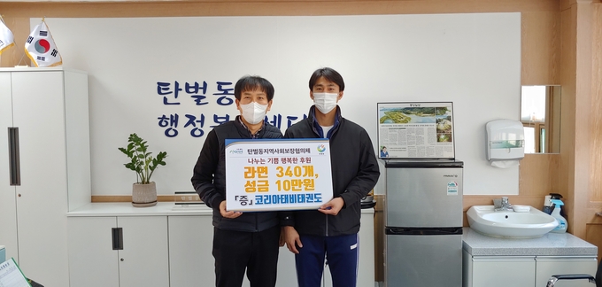 코리아 태비태권도장 연수흠 관장이 어려운 이웃에게 전달해 달라며 탄벌동 행정복지센터를 찾아 전재현동장에게 성금과 물품을 전달하고 있다. (사진=광주시 제공)