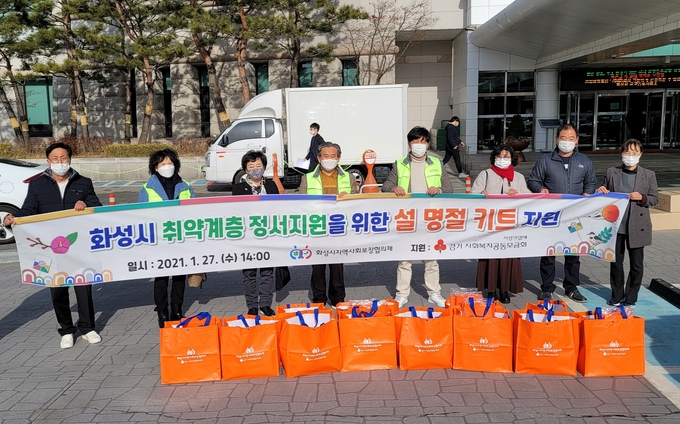 화성시지역사회협의체가 설 명절을 앞두고 지역 취약계층을 위한 식료품키트를 전달한 후 기념촬영을 하고 있다.(사진=화성시 제공)