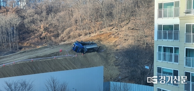 지난 1일 오후 수원시 영통구 영흥공원 조성 공사 현장에서 25t 덤프트럭이 넘어지는 사고가 발생했다. 사고 현장 비탈길 아래에는 인근 아파트 단지가 위치해 자칫 대형 사고로 이어질 수 있었던 아찔한 모습이다. (사진=독자 제공)