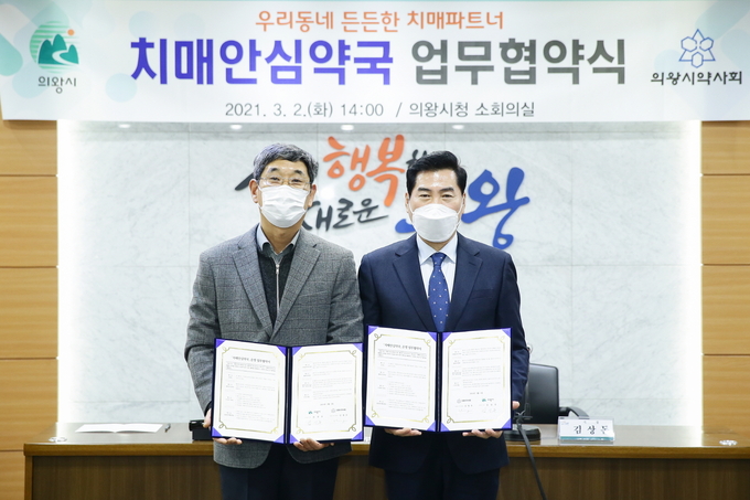 김상돈 의왕시장이 신정무 의왕시약사회장과 ‘치매안심약국’ 업무협약을 체결한 뒤 협약서를 들어보이고 있다. (사진=의왕시 제공)