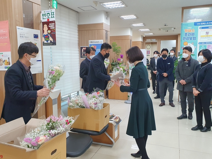 농협중앙회 경기검사국이 송산농협 종합감사 때 임직원들에게 꽃을 나눠주며 코로나 19로 화훼농가를 돕기 위한 소비촉진에 앞장섰다.(사진/=농협화성시지부 제공)<br>
