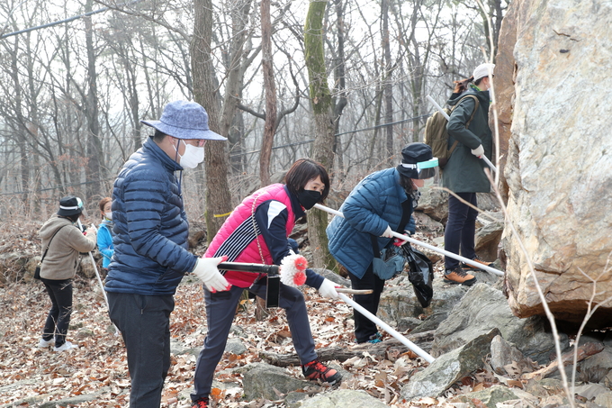 한대희 시장(왼쪽 파란색 점퍼)이 군포시 공무원 자원봉사자들과 함께 수리산에서 바위밑 매미나방 알집을 제거하고 있다.(사진= 군포시 제공)