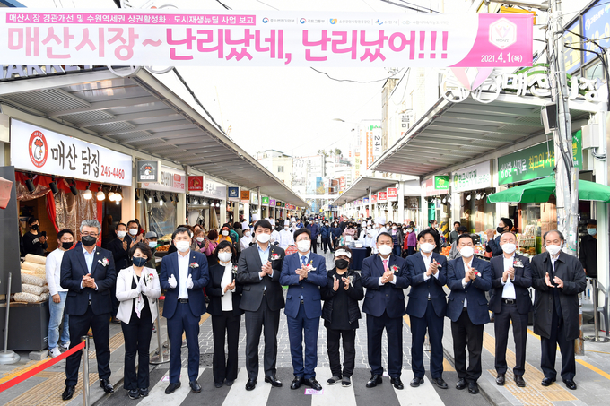 염태영 시장(오른쪽 7번째)과 참석자들이 경관개선사업을 마친 매산시장 앞에서 함께하고 있다. (사진=수원시 제공)