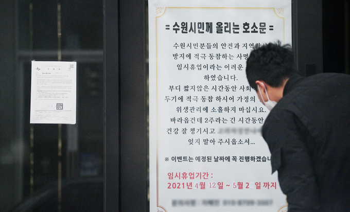 코로나19 확산방지를 위해 수도권과 부산 지역 유흥시설의 영업이 3주간 금지된 12일 수원시 한 유흥업소에서 관계자가 집합금지 행정명령 안내문 옆에 호소문을 걸고 내용을 확인하고 있다. (사진 = 조병석 기자)