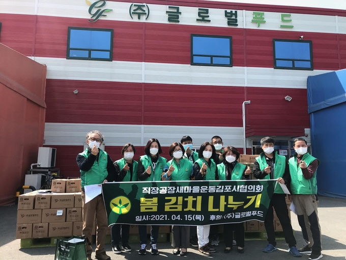 직장새마을운동김포시협의회 회원들이 봄김치 앞에서 김치전달에 앞서 기념촬영을 하고 있다.