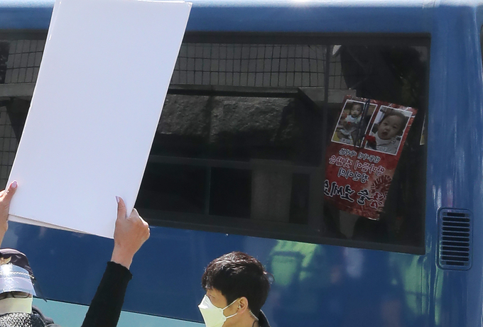 지난 14일 16개월 된 입양 딸 정인 양을 학대해 숨지게 한 혐의로 기소된 양부모 결심 공판이 열리는 서울남부지법 입구에서 시민들이 양모가 탑승한 것으로 보이는 호송차를 향해 팻말을 들고 항의하고 있다. (사진=연합뉴스 제공)