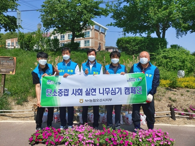 NH농협 오산시지부 임직원과 직원들이 탄소중립 사회 실현을 위한 나무심기 캠페인 후 기념촬영을 하고 있다.