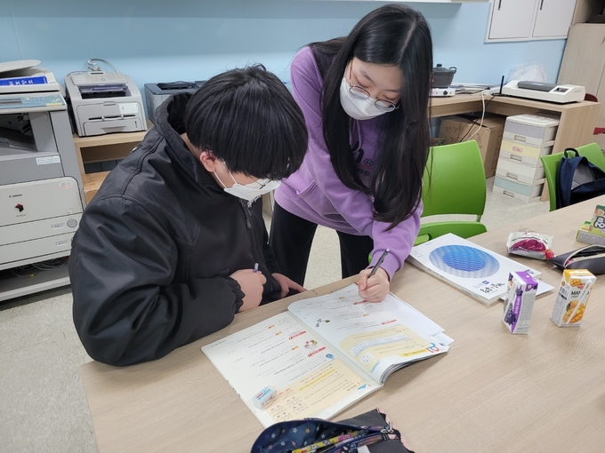 방과후아카데미에 참여한 한 중학생이 대학생 멘토에게 영어 멘토링을 받고 있다.(사진=화성시여성가족청소년재단 제공)