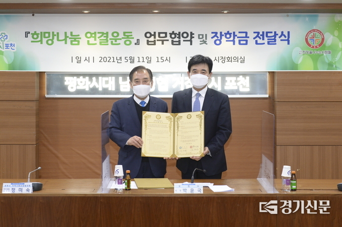 박윤국 포천시장과 김정안 ㈔희망을나누는사람들 회장이 서명한 협약서를 들어 보이고 있다. (사진=포천시 제공)