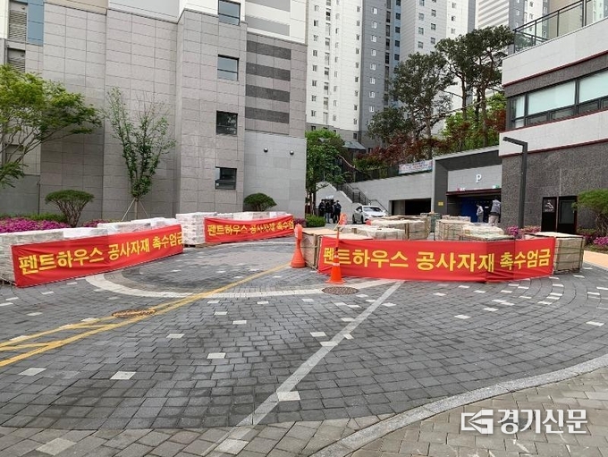 지난 5일과 7일 시공사 용역 일당이 경기 용인시 수지구 롯데캐슬 파크나인 1차 아파트 입구에 건설자재를 무단 적치시킨 이후, 경고성 현수막을 교체해 두른 모습. (사진=제보자 제공)