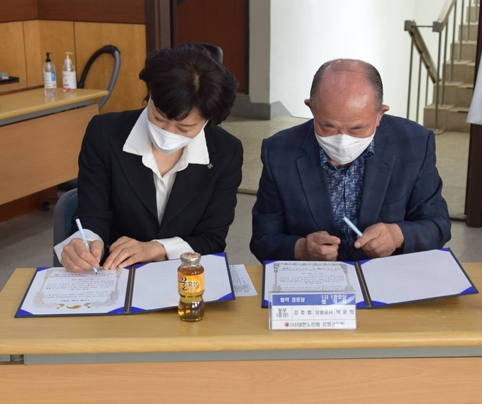 박윤희 양평공사 사장과 강호범 동부중앙경로당 회장이 1사 1경로당 협약서에 서로 서명을 하고 있다. (사진=양평공사 제공)