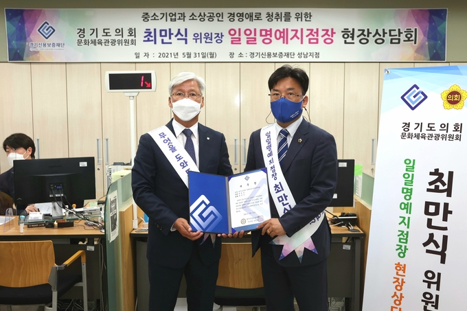 이민우 경기신용보증재단 이사장(왼쪽)이 31일 성남지점에서 최만식 경기도의회 의원을 일일명예지점장으로 위촉했다. (사진= 경기신보 제공)