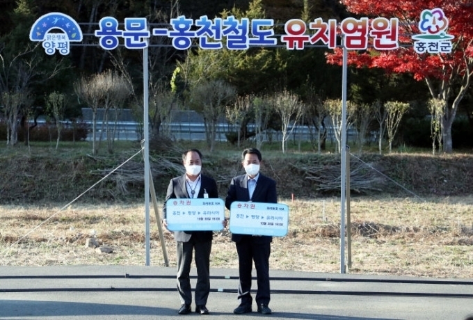 정동균 양평군수와 허필홍 강원 홍천군수가 용문-홍천선 국가철도망 유치를 염원하는 푯말을 들고 있다. (사진=양평군 제공)