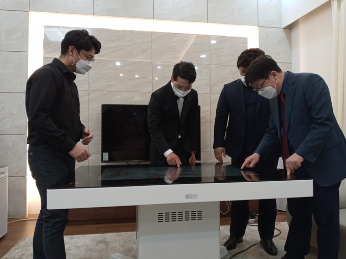 가수 박군(왼쪽 두번째)이 고령자 인지 능력 향상 및 치매질환을 개선하는 차세대 헬스케어 기기인 해피테이블을 작동해 보고 있다. (사진=김대성 기자)