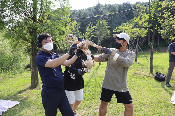 한대희 시장(왼쪽)이 헤드폰을 끼고 청년들과 함께‘ 사일런트 아트 워킹 투어’를 하면서 종이인형을 만들고 있다..(사진= 군포시 제공)<br>
