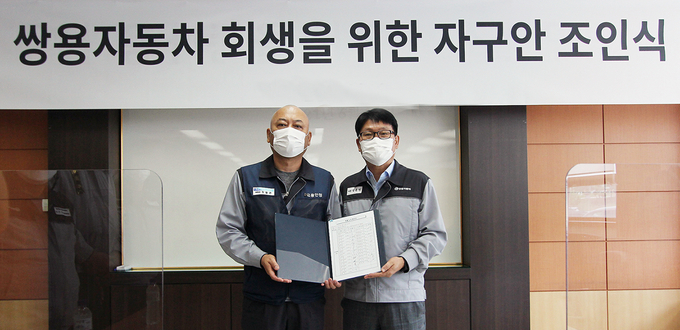 쌍용자동차는 14일 평택공장에서 노사 대표가 참석한 가운데 회사 회생을 위한 조인식을 진행했다. 사진은 정용원 관리인(오른쪽)과 정일권 노동조합 위원장(왼쪽)이 합의안에 서명한 후 기념촬영을 하는 모습. (사진=쌍용자동차 제공)