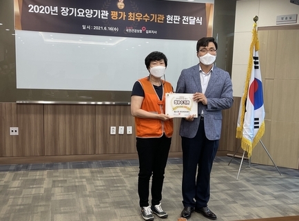 노인주간보호기관 김정숙 김포헬스원데이케어센터장이 국민건강관리공단에서 수여한 최우수기관 명패를 받고 기념사진을 찍고 있다.(사진=김포헬스원데이센터 제공)