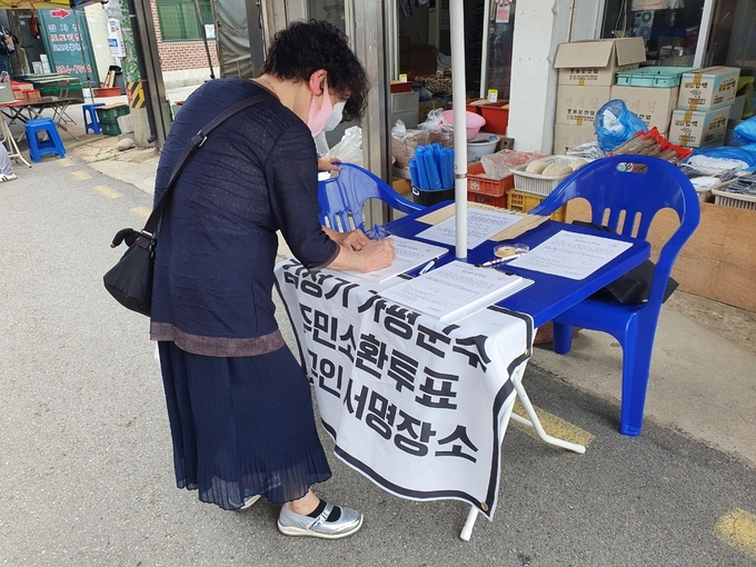 가평군수 주민소환투표 청구인 서명장소에서 한 시민이 서명을 하고 있다. (사진=가평군 공동형 장사시설 반대 대책위원회 제공)