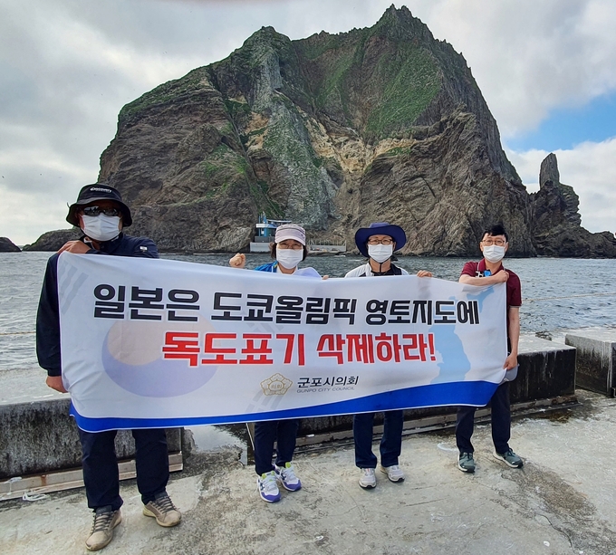 군포시의회 의원들이 독도를 방문해 도쿄올림픽 일본 지도에 표기한 독도를 삭제할 것을 촉구하는 현수막을 들고 있다. (사진=군포시의회 제공)