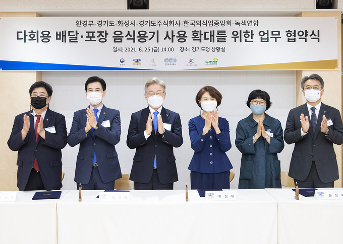 이재명 경기도지사(왼쪽 세 번째)가 25일 경기도청에서 한정애 환경부장관, 서철모 화성시장, 이석훈 경기도주식회사 대표이사, 방대환 한국외식업중앙회 경기도남부지회장, 윤정숙 녹색연합 대표와 다회용 배달·포장 음식용기 관련 업무협약을 체결하고 있다. (사진= 경기도 제공)