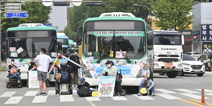 지난해 수원시 팔달구 도청 오거리에서 열린 장애인 권리 보장 촉구 결의 대회에 참석한 경기장애인차별철폐연대 관계자들이 시내버스와 도로를 점거한 채 집회를 하고 있다. (사진=경기신문 DB)
