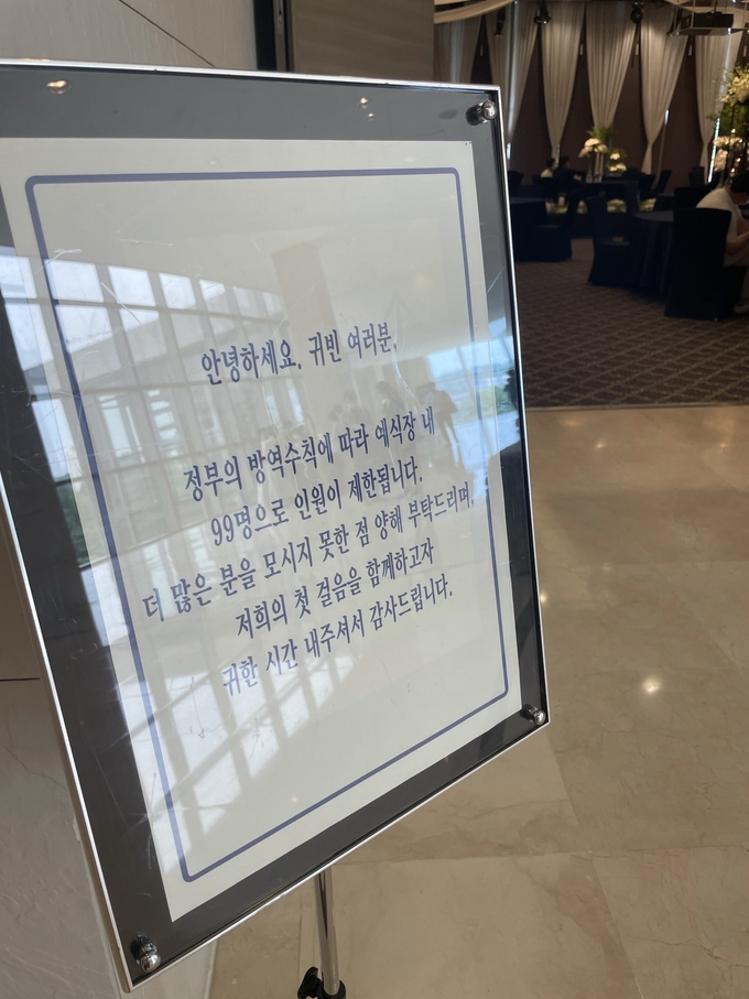 지난 10일 한 결혼식장 입구에 참석 인원이 99명으로 제한된다는 표지판이 놓여있다. ( 사진 = 조경욱 기자 )
